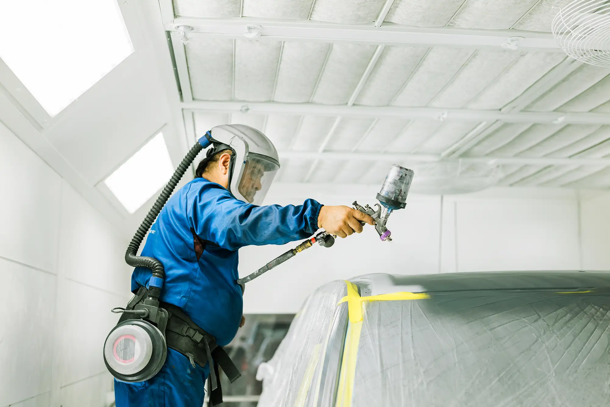 Caliber Collision Paint Tech painting repaired car.